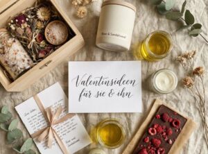 30 außergewöhnliche Valentinstagsgeschenke für sie & ihn: die keiner erwartet (aber jeder liebt!) Flatlay mit Valentinsgeschenkideen auf Leinenstoff: Wellness-Box mit Kräutern, Duftkerze, Naturkosmetik, Liebesbrief und Schokolade, dazu ein handschriftlicher Zettel mit „Valentinsideen für sie & ihn“.